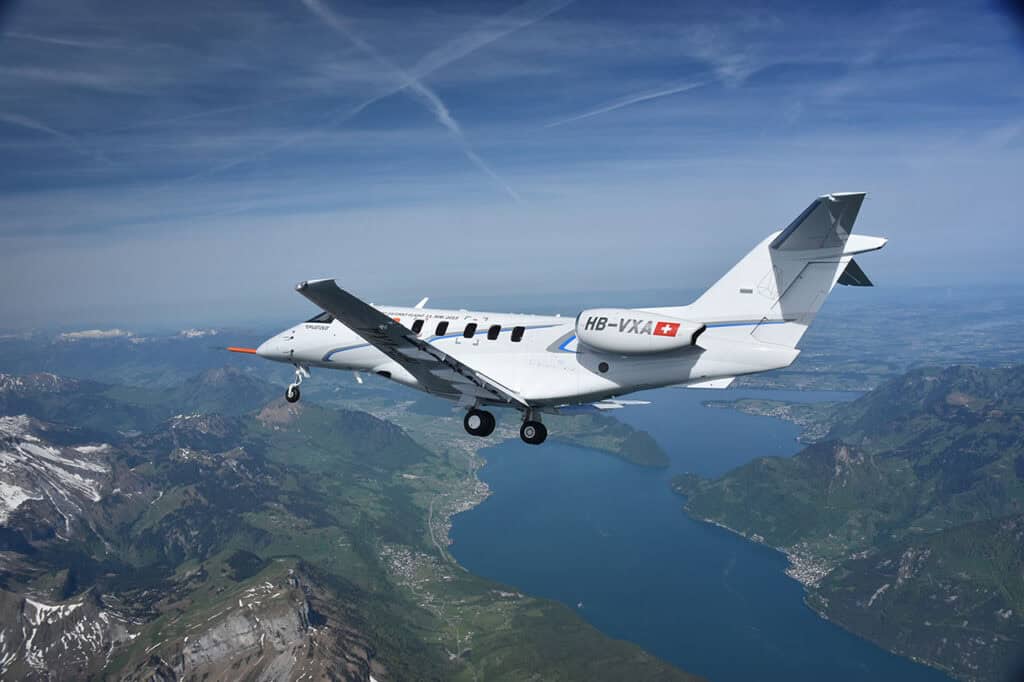 Aircraft in flight during maiden voyage over scenic landscape.