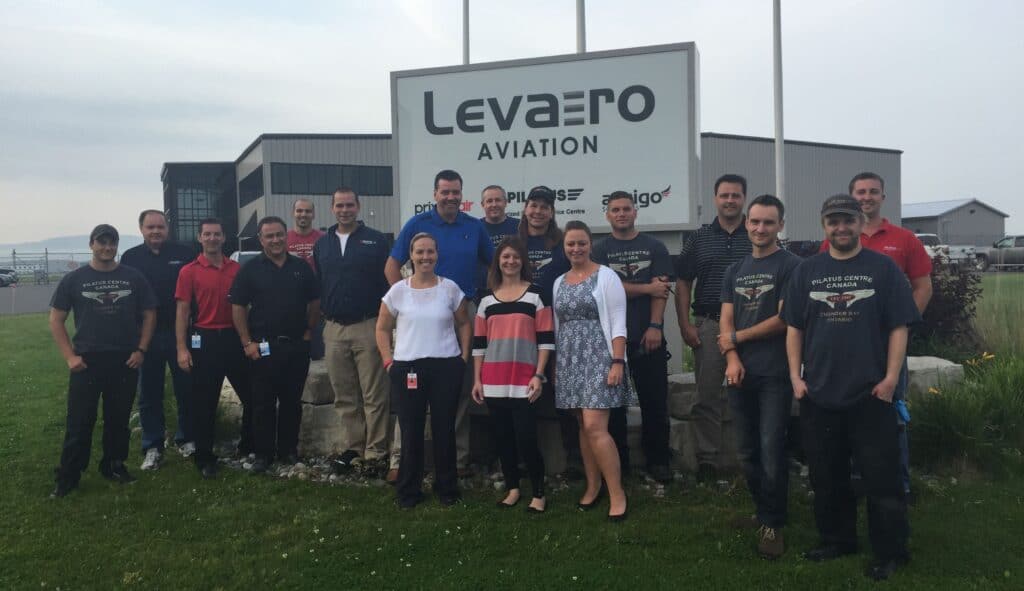 Levaero Aviation team standing outside their facility in front of the sign.