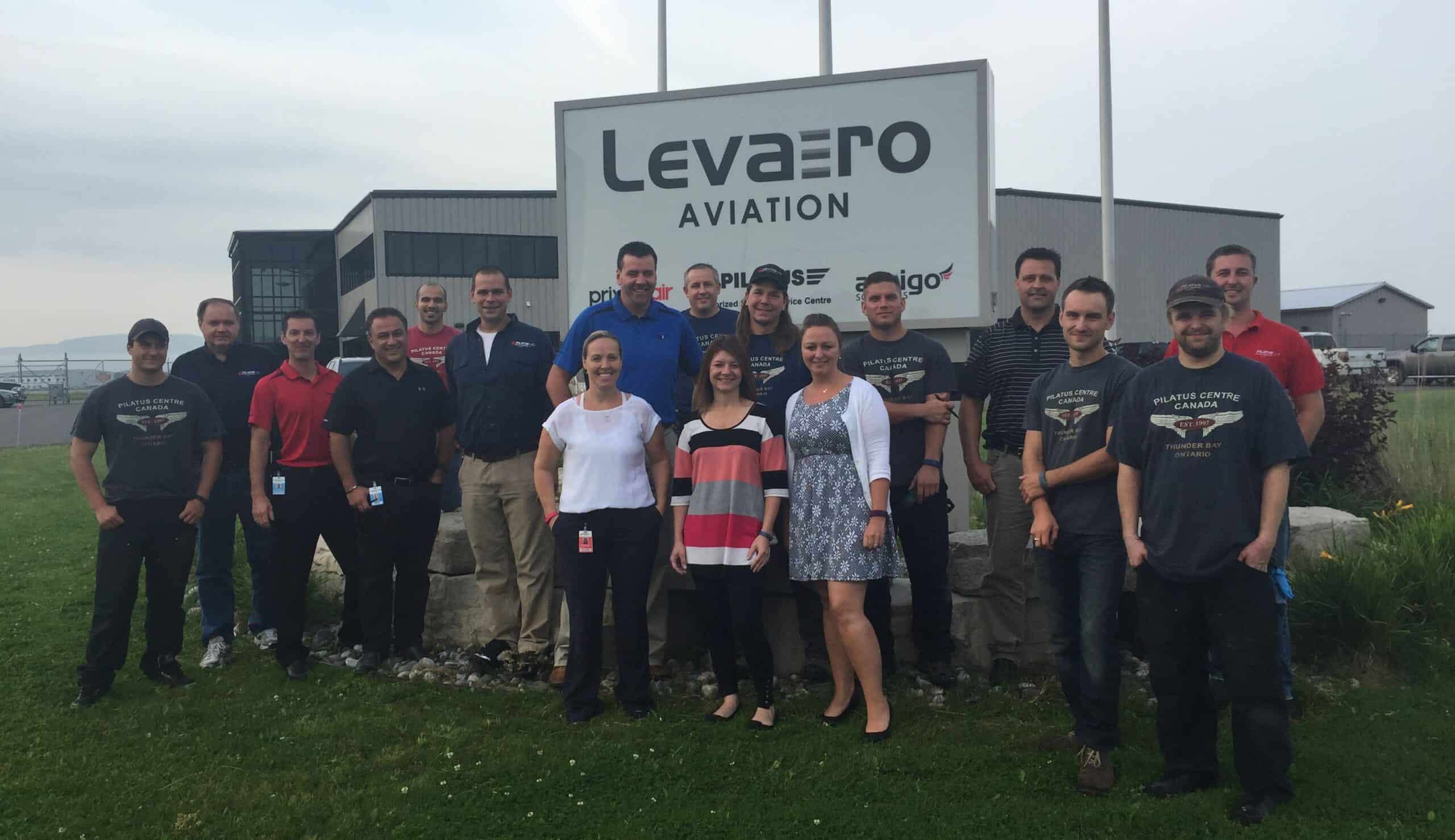 Levaero Aviation team standing outside their facility in front of the sign.