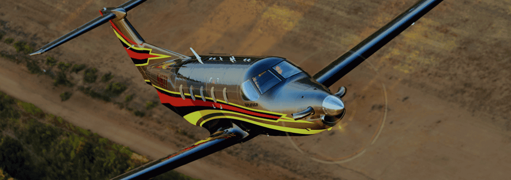 Aircraft flying over open landscape, showcasing advanced aviation technology.