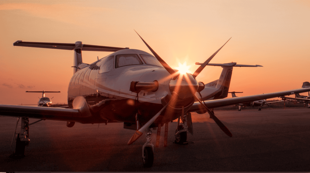 Aircraft on tarmac at sunset with sunburst effect.