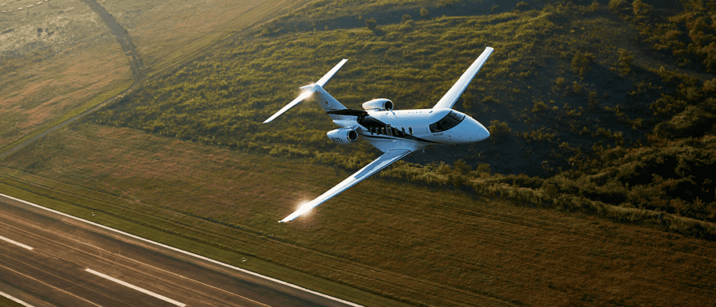 Pilatus PC-24 super versatile jet flying over a runway.