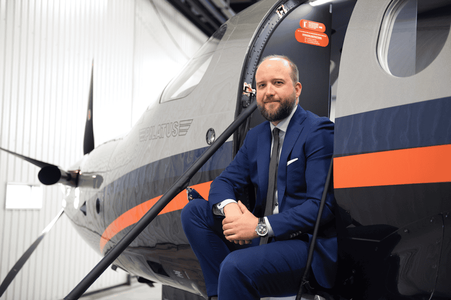 Man in blue suit sitting on helicopter stairs at Levaero aviation facility.