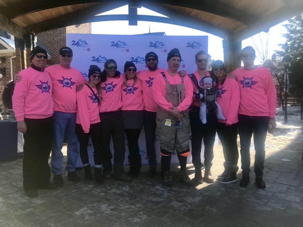 Group of Levaero team members in pink shirts at ski relay event.