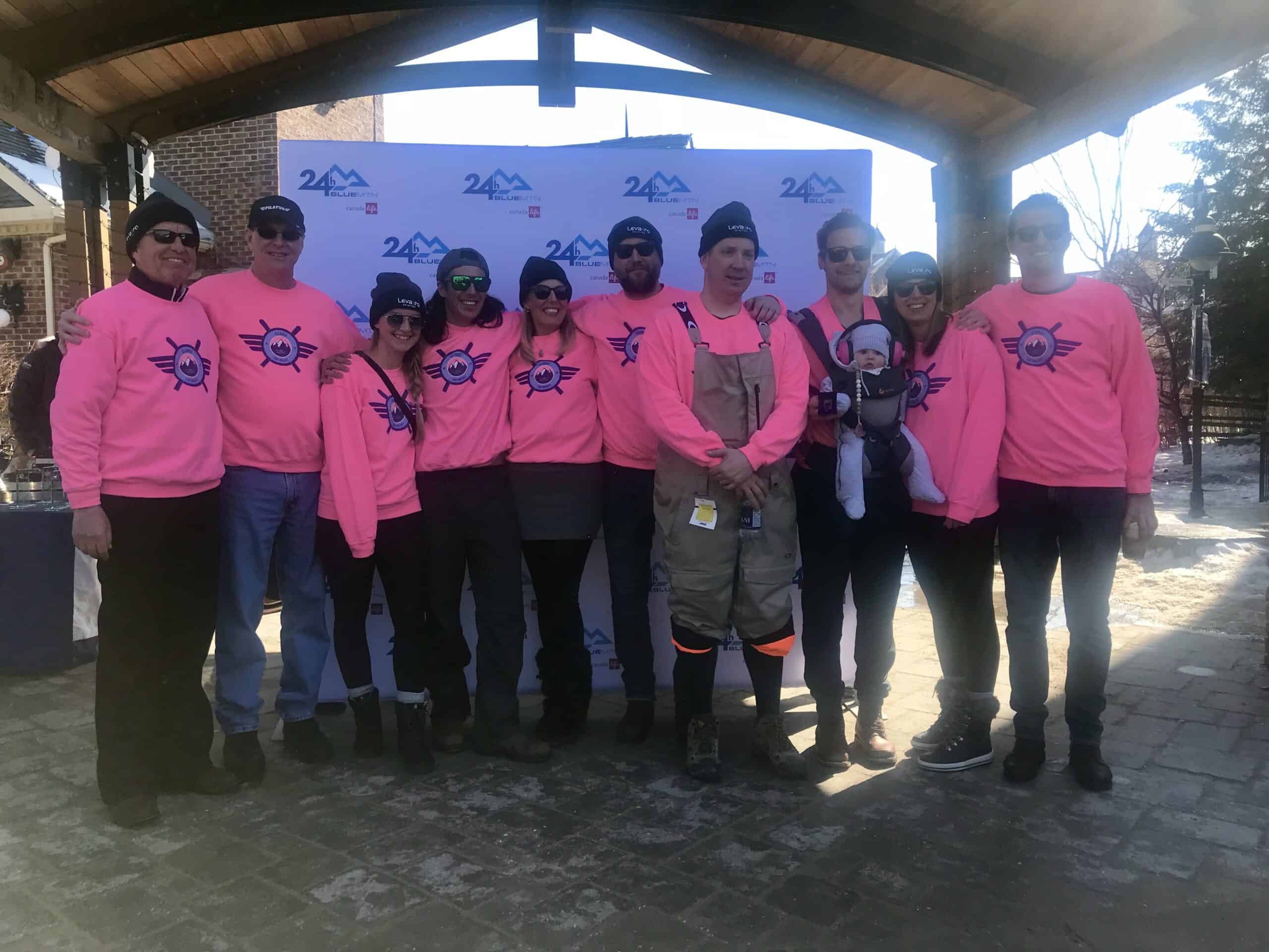 Group of Levaero team members in pink shirts at ski relay event.