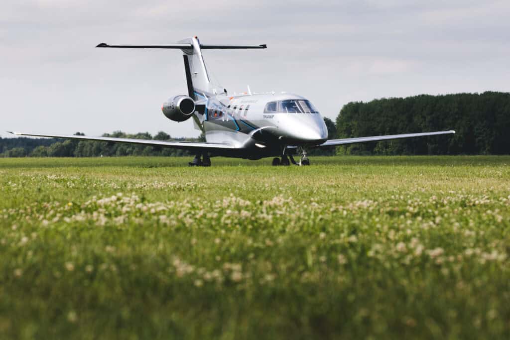 Private jet aircraft parked on grassy airfield.