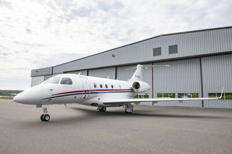 Embraer Legacy 450 jet parked outside a hangar, showcasing luxury private aircraft.