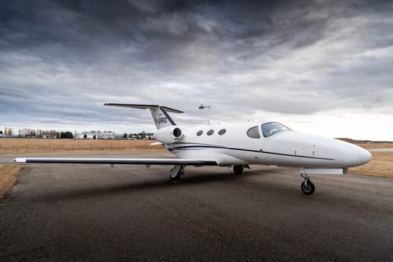 Private jet parked on the runway with a cloudy sky background.