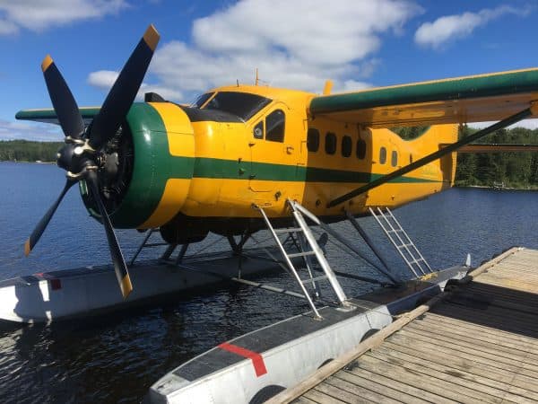 Vintage de Havilland DHC3 Otter seaplane on water near dock.