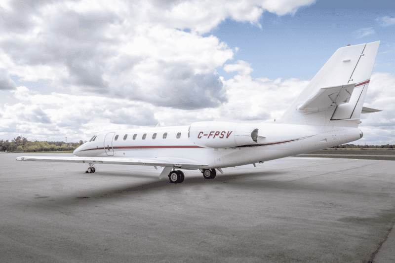 Private jet aircraft on runway with cloudy sky background.