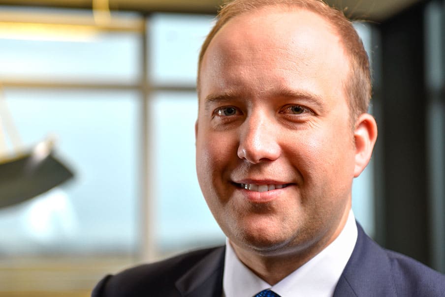 Professional businessman in a suit smiling in an office setting.
