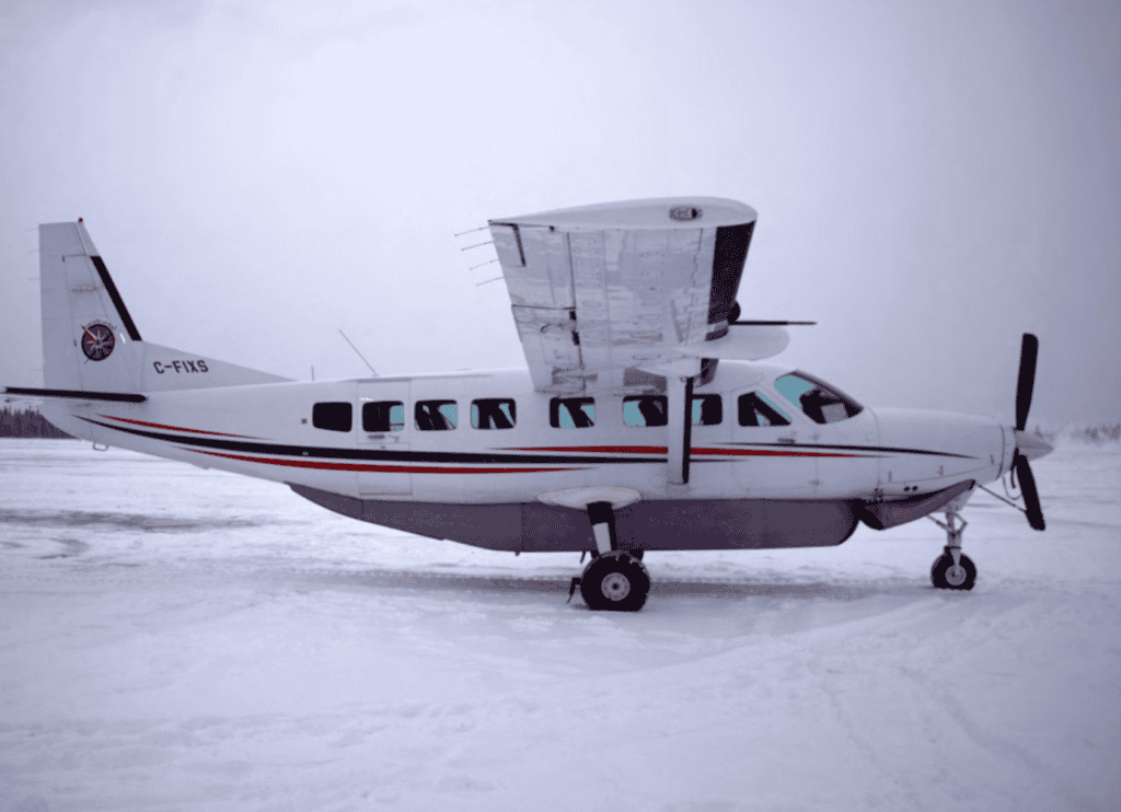 Cessna Grand Caravan 208B aircraft parked on snow-covered ground.