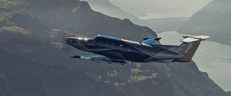 Aircraft in flight over scenic mountains and water.