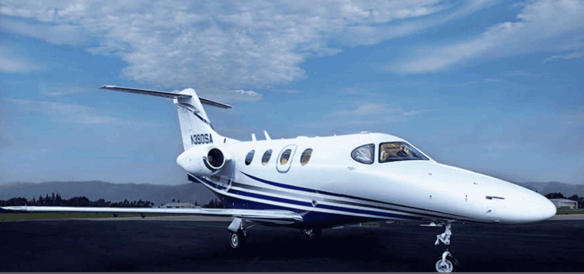 Private jet on runway with blue sky background.
