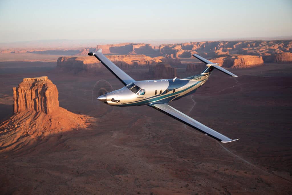Private jet flying over a canyon landscape at sunset.