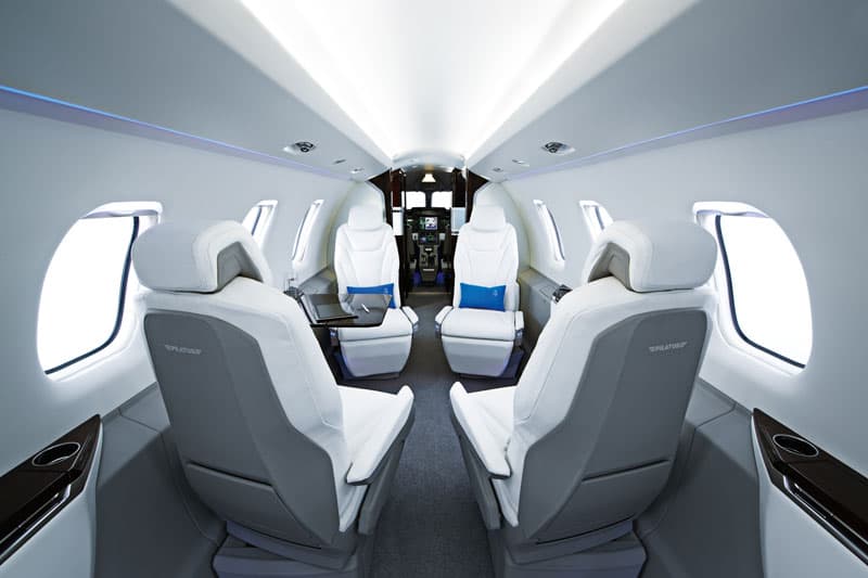 Modern interior of a Pilatus PC-24 business jet with luxurious seating.