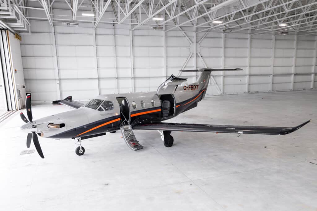 Private jet aircraft parked inside hangar with open door.