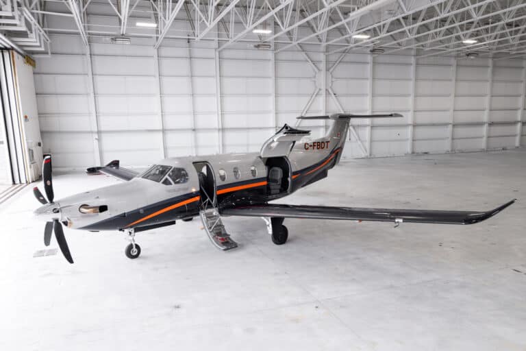 Private jet aircraft parked inside hangar with open door.