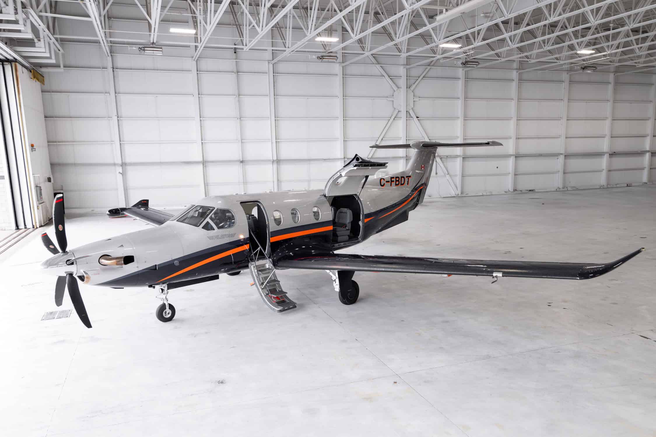 Private jet aircraft parked inside hangar with open door.