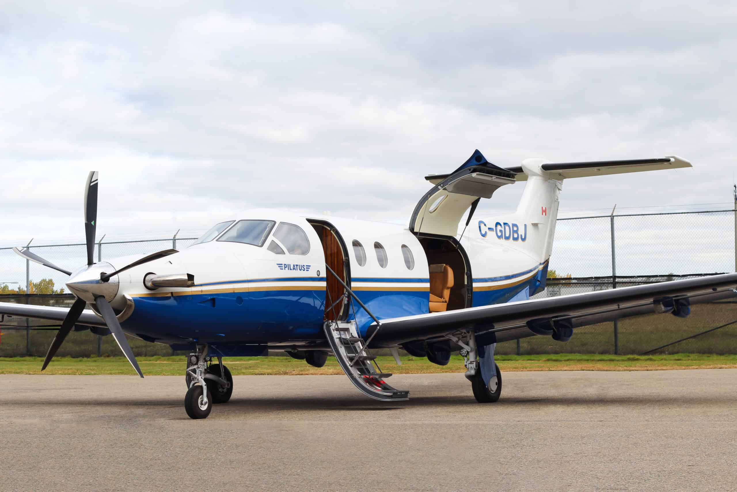 Pilatus PC-12 NG turboprop aircraft on runway with open door.