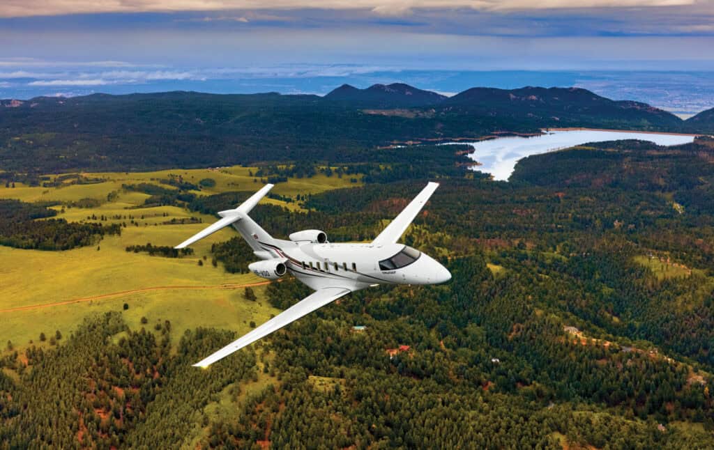 Aircraft flying over lush green landscape in Canada.