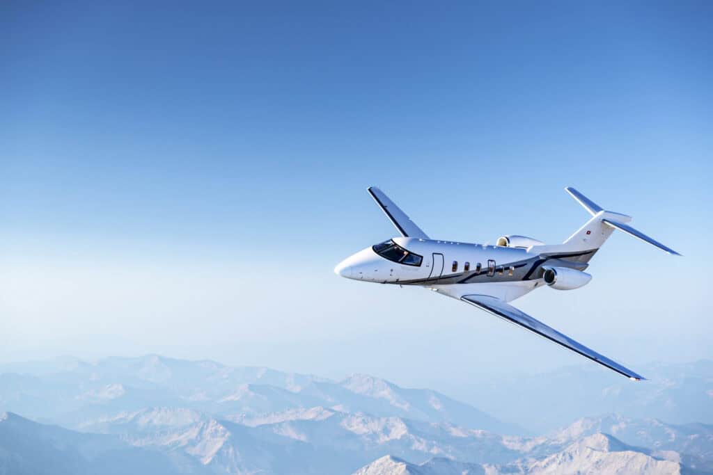 Private jet flying over mountains, Levaero aviation services.
