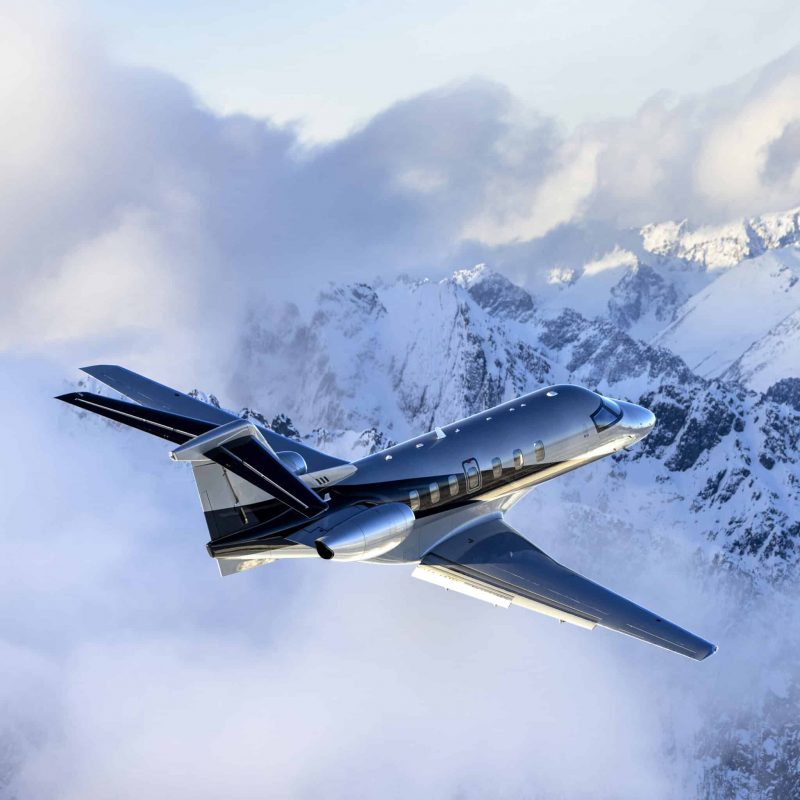 Private jet flying over snow-covered mountains for sale.